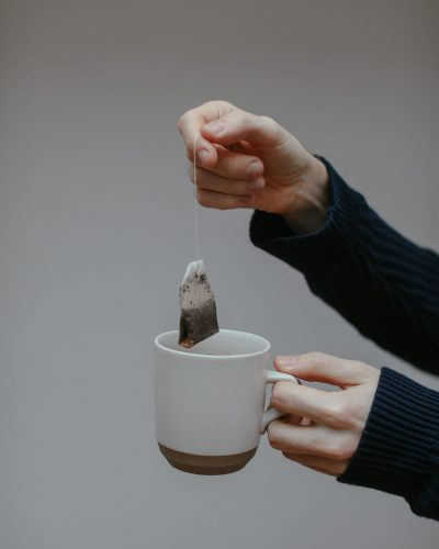 hand holding a cup of tea with tea bag